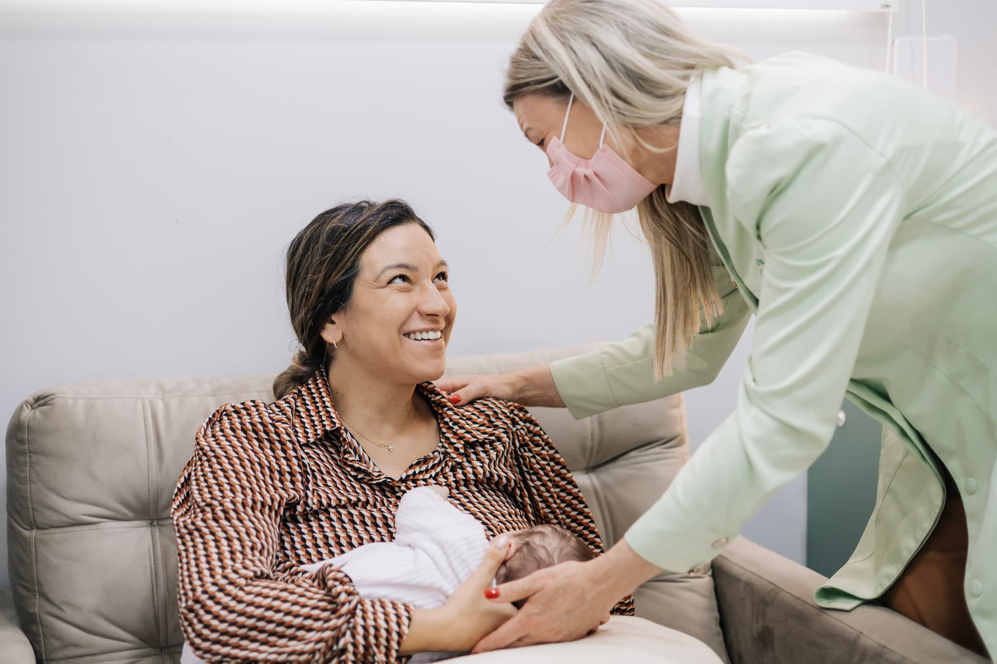 Mãe amamentando com apoio de consultora